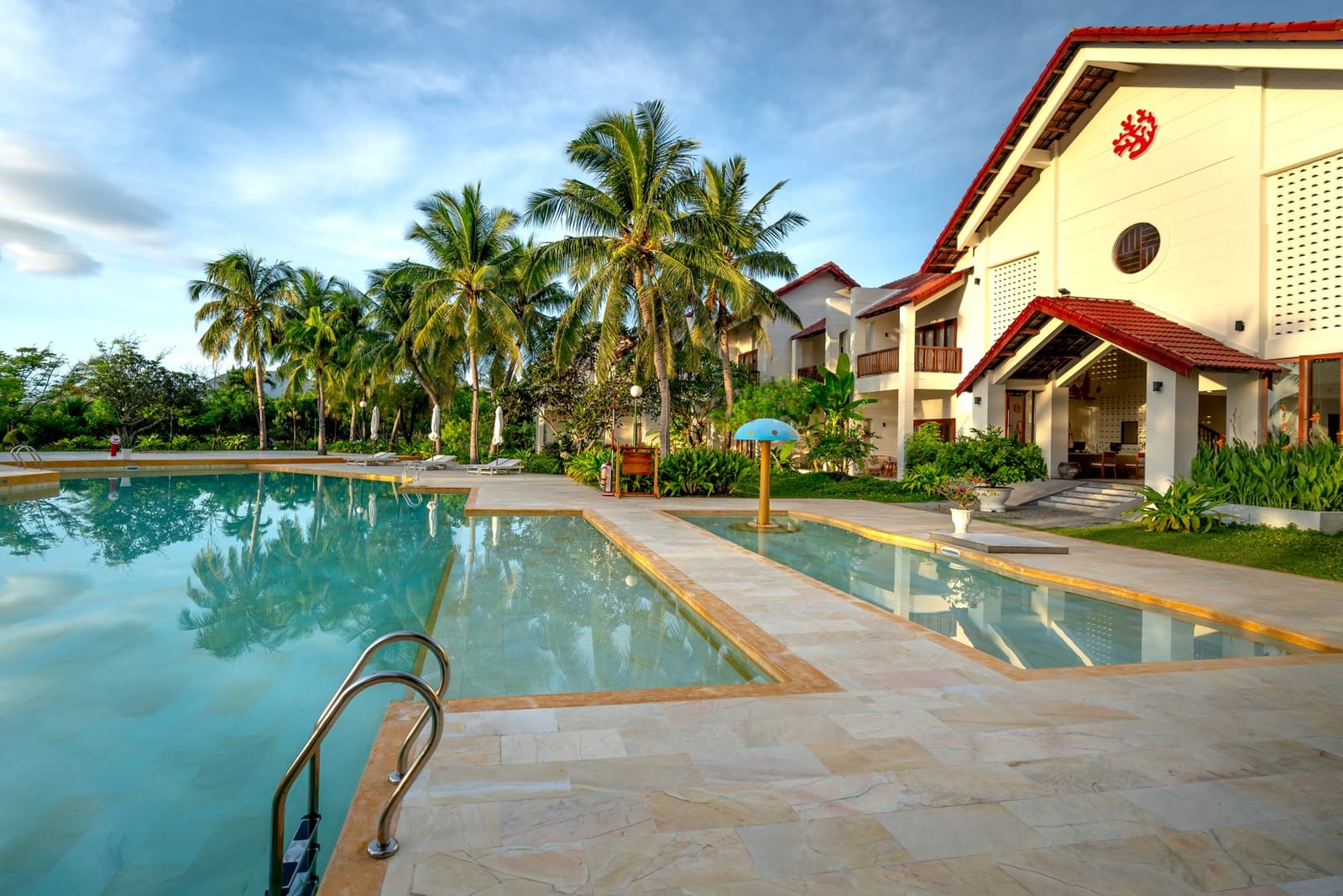 Resort building beside a swimming pool and palms
